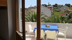 A balcony with a table and chairs, overlooking a residential area with houses and a church. - Beach Villa Olivia (Lumbarda)