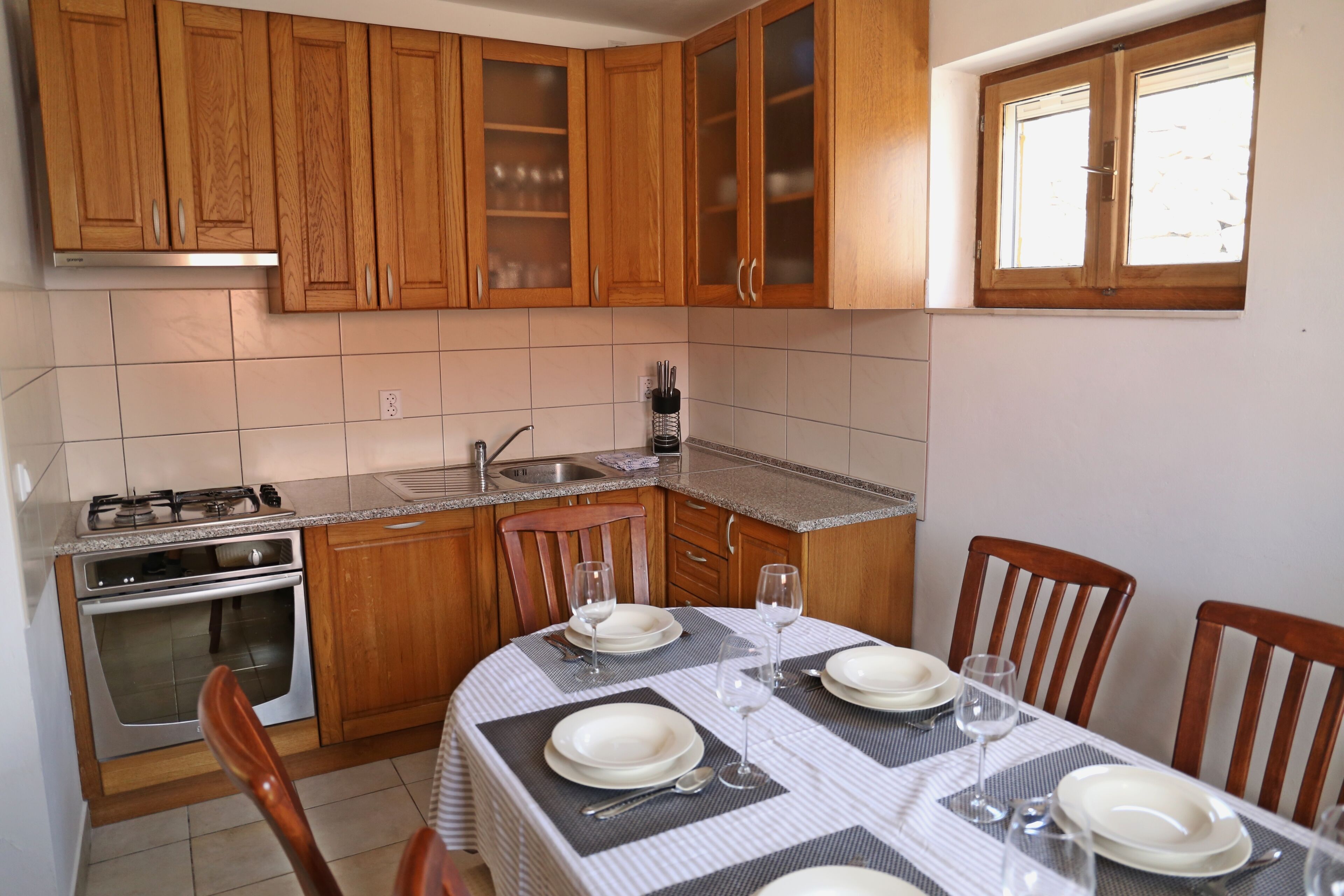 A kitchen with wooden cabinets, a gas stove, and a dining table set for four.