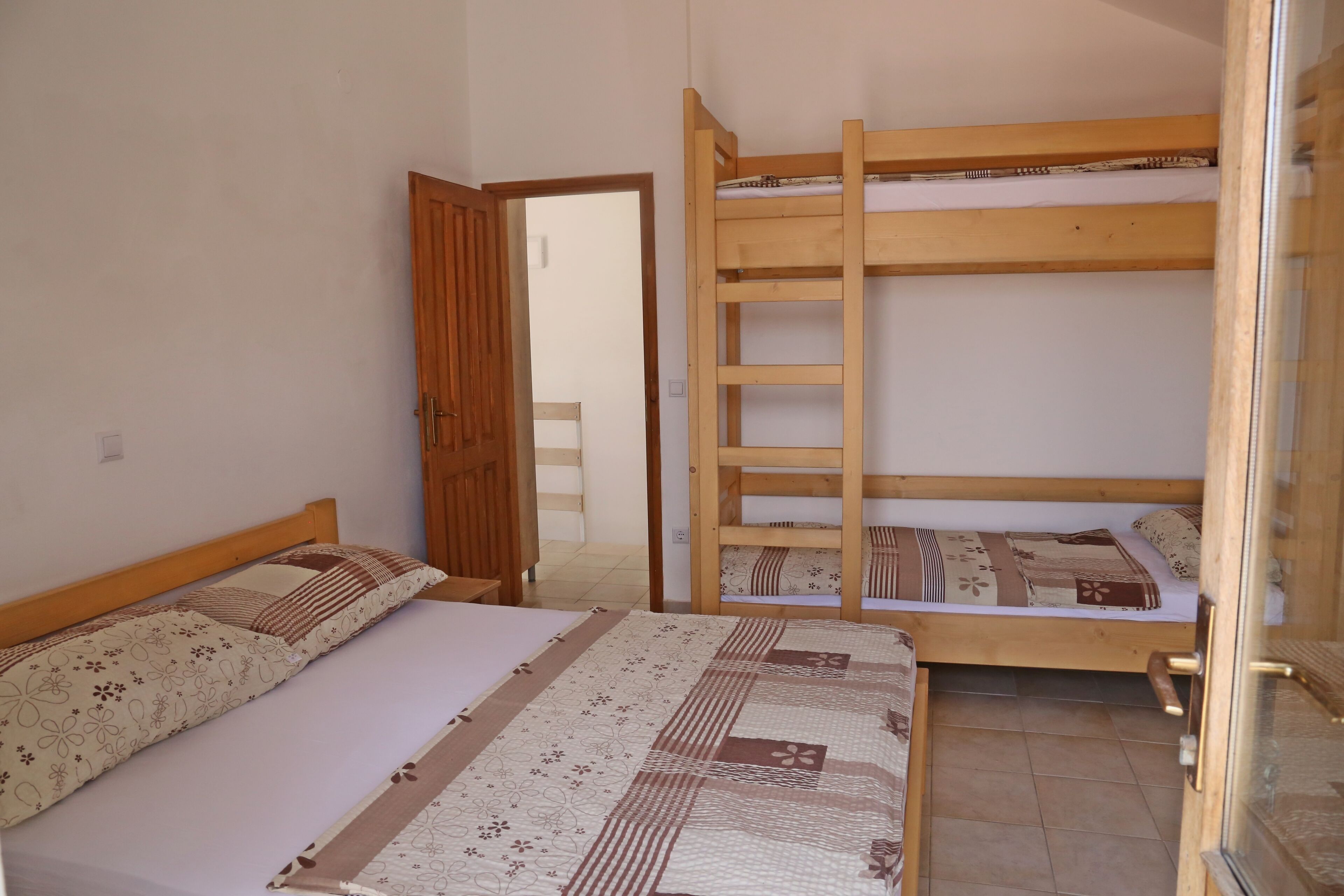 Une chambre avec deux lits, l’un doté d’un cadre en bois et l’autre d’un cadre en métal. Une échelle en bois est fixée au lit en métal.