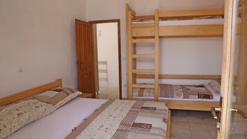 Une chambre avec deux lits, l’un doté d’un cadre en bois et l’autre d’un cadre en métal. Une échelle en bois est fixée au lit en métal.