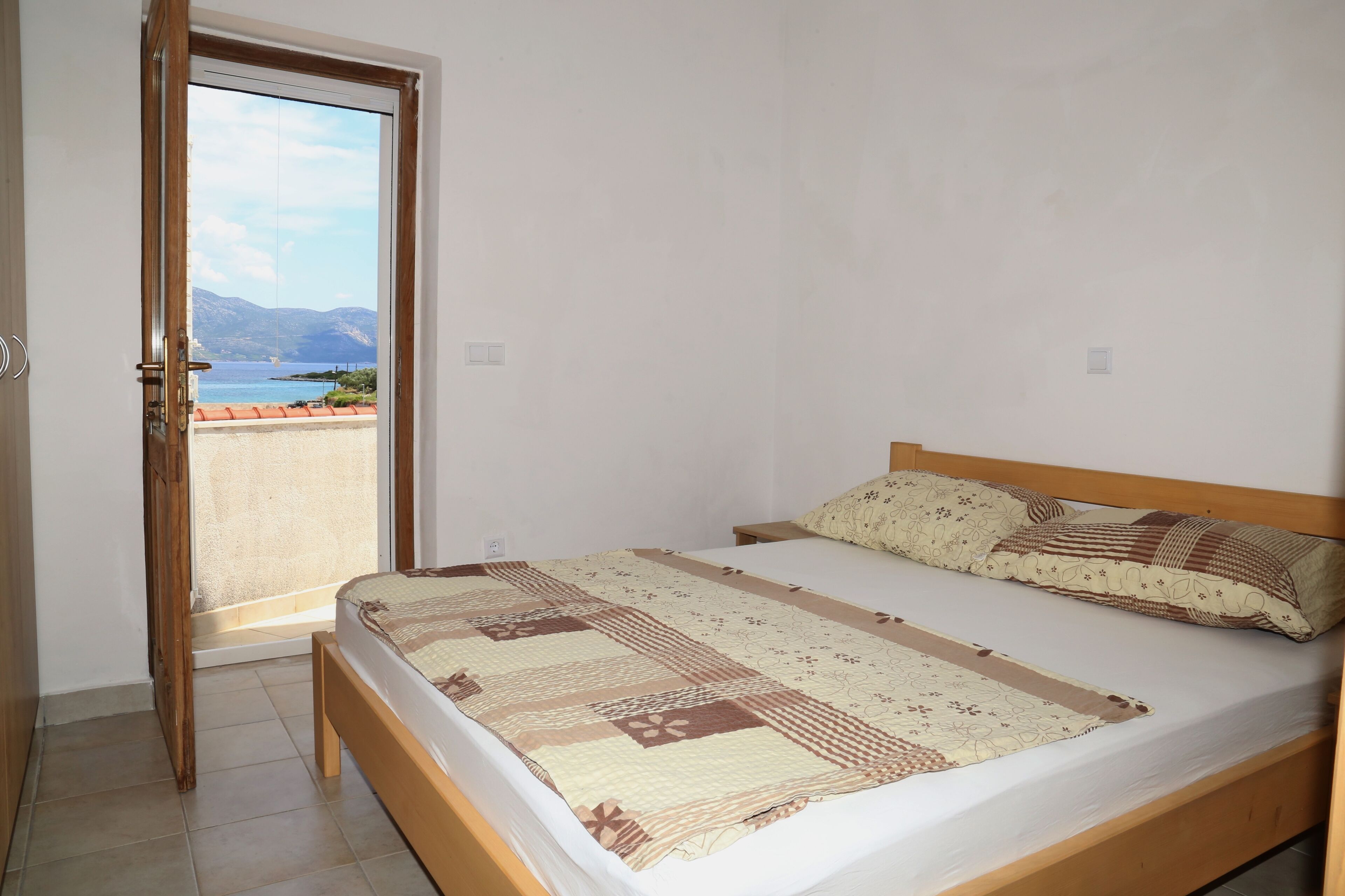A bedroom with a bed, a view of the sea, and a balcony.