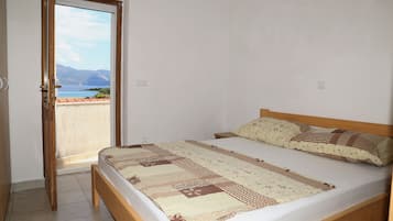 A bedroom with a bed, a view of the sea, and a balcony.