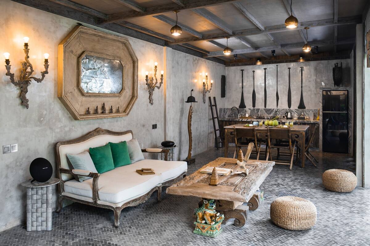 A rustic room with a wooden sofa, a dining table, and a kitchen area.