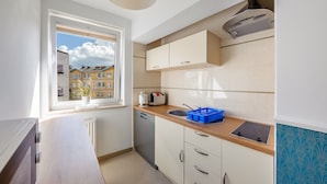 A compact kitchen with a window, a toaster, a kettle, and a blue dish rack. - Apartamenty Sun & Snow Mare Promenada (Miedzyzdroje)