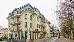A multi-story hotel with balconies, a ground floor restaurant, and a paved sidewalk. - Apartamenty Sun & Snow Mare Promenada (Miedzyzdroje)