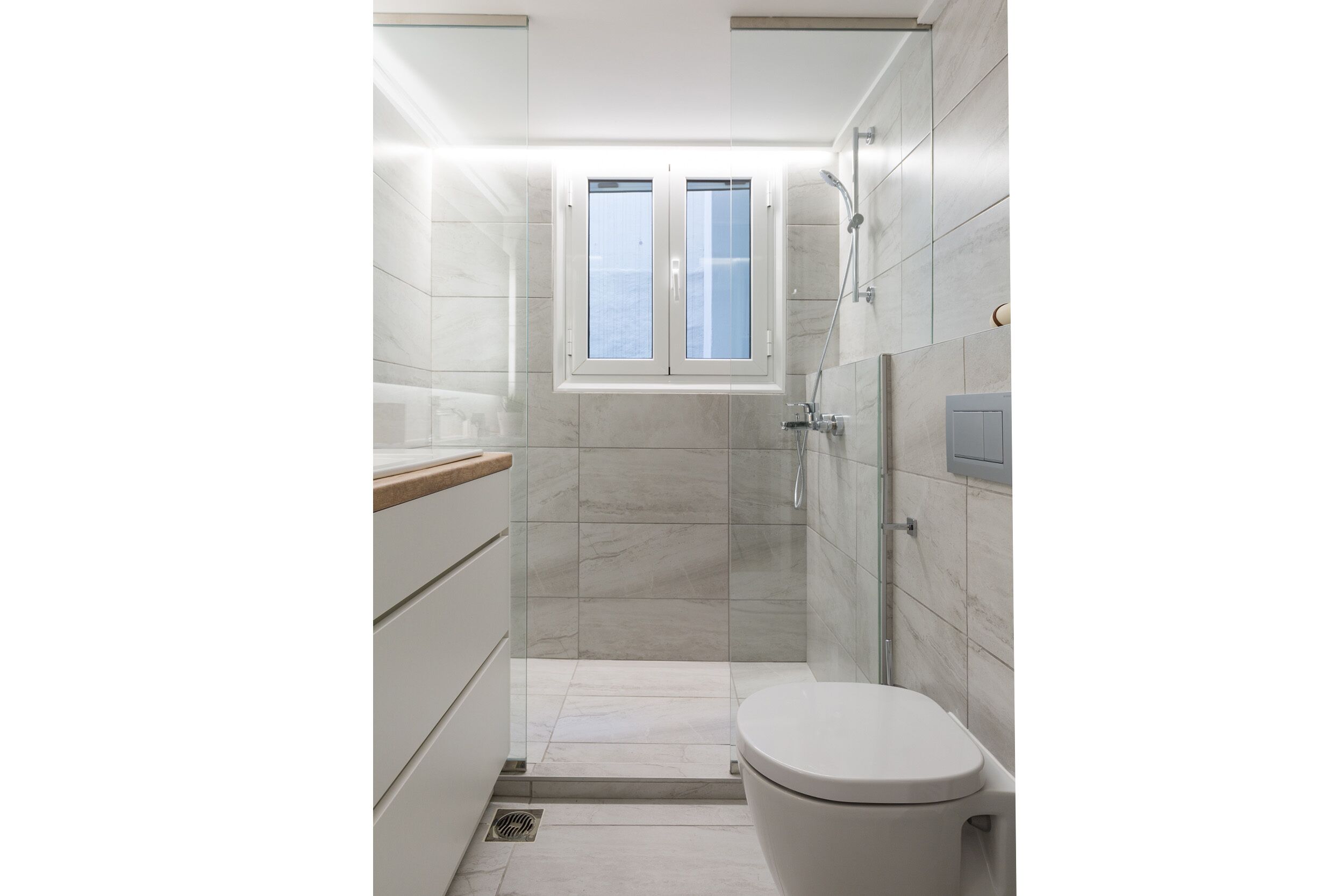 A modern bathroom with a toilet, a shower, and a window.