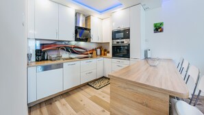 A modern kitchen with white cabinets, a wooden countertop, and built-in appliances. - Apartamenty Sun & Snow Zwyciestwa (Miedzyzdroje)
