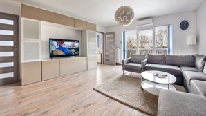 A modern living room with a flat-screen TV, grey sofa, and a coffee table. - Apartamenty Sun & Snow Zwyciestwa (Miedzyzdroje)