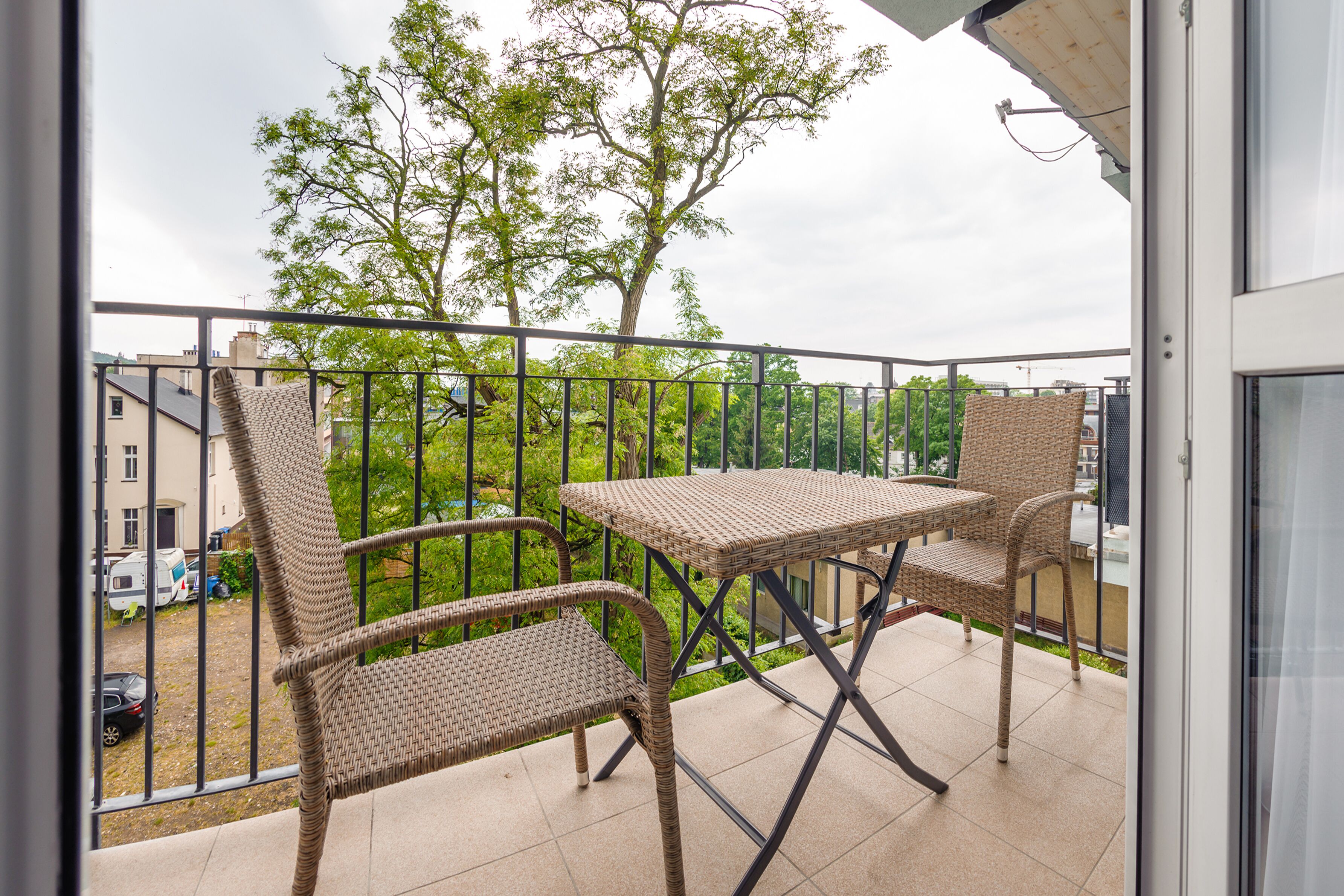 A balcony with wicker furniture, a table, and chairs.