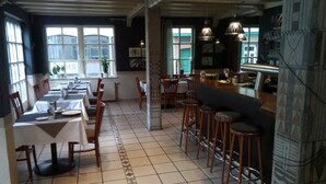 A restaurant with long communal tables and high stools, a bar area, and large windows with views. - Hotel Loewensteiner Hof Haus am Neuplatz (Wertheim)