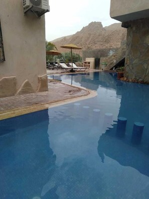Una piscina al aire libre, sombrillas, tumbonas