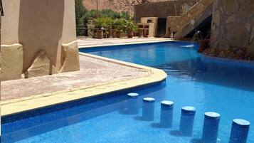 Alberca al aire libre, sombrillas en la alberca y camastros