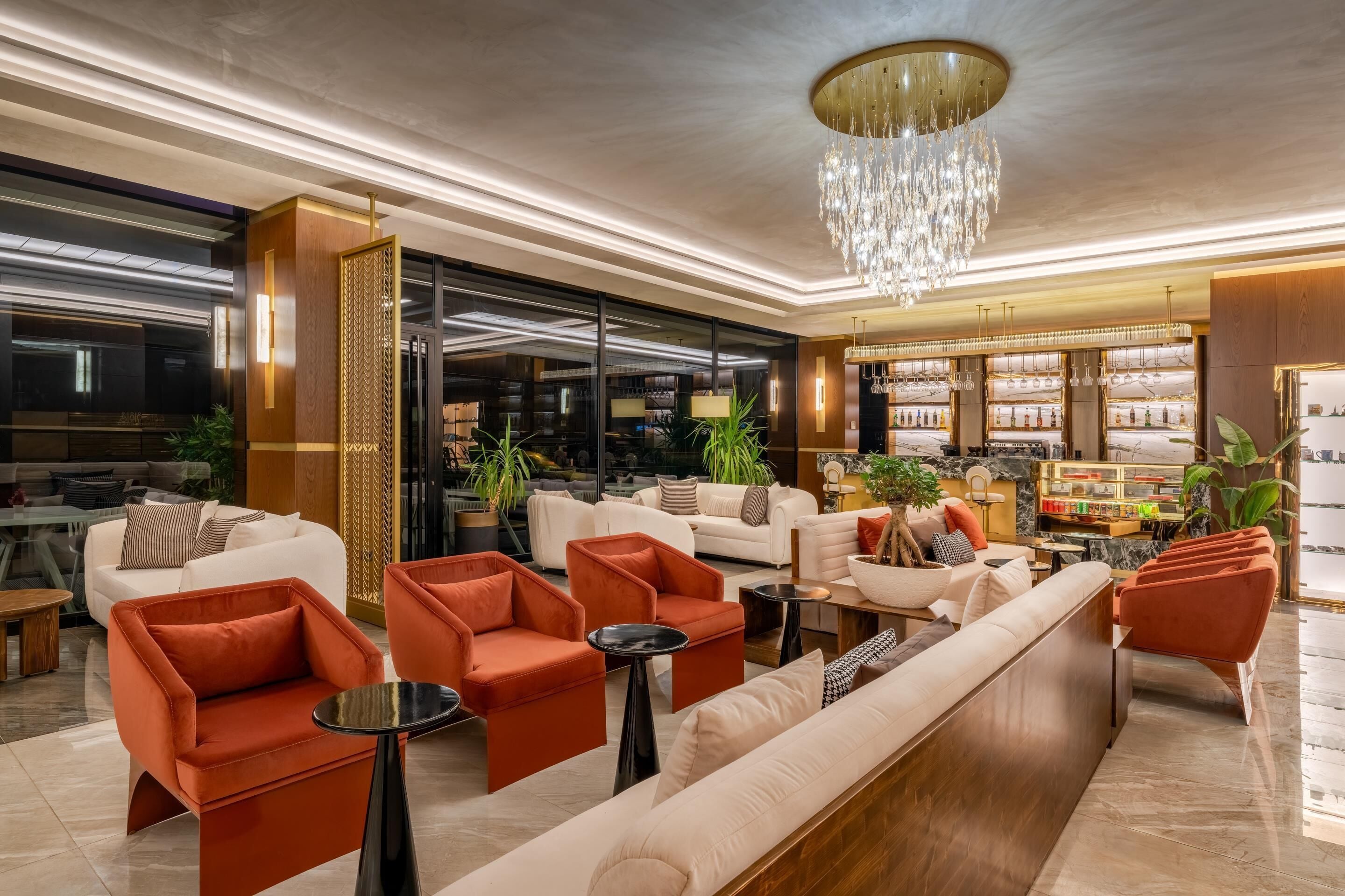 A modern lobby with plush seating, a chandelier, and a bar area.