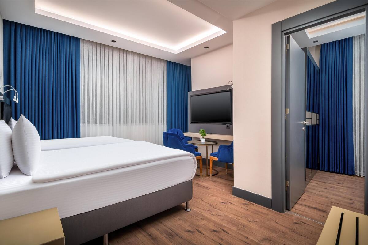 Une chambre d’hôtel moderne, dotée d’un grand lit, d’un bureau et d’une télévision.