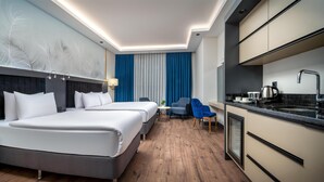Ein Hotelzimmer mit zwei Betten, einer Essecke und einer Küchenzeile.