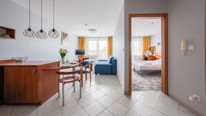 A modern hotel room with a dining area, a sofa, and a bed. - Apartamenty Sun & Snow w Rezydencji Bielik (Miedzyzdroje)