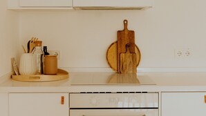 Une cuisine avec des armoires blanches, une planche à découper en bois et un four encastré.