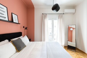 Ein Schlafzimmer mit Bett, Nachttisch, Spiegel und einem Fenster mit Vorhängen.