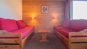 Une pièce chaleureuse avec deux lits en bois, une petite table et deux lampes fixées au mur.