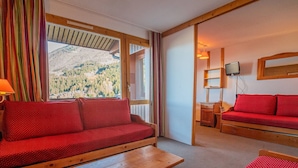 Une pièce chaleureuse avec un canapé rouge, une table en bois et un lit avec une literie rouge.