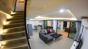 Una sala de estar moderna con un sofá gris, una mesa de centro y una escalera con escalones iluminados.