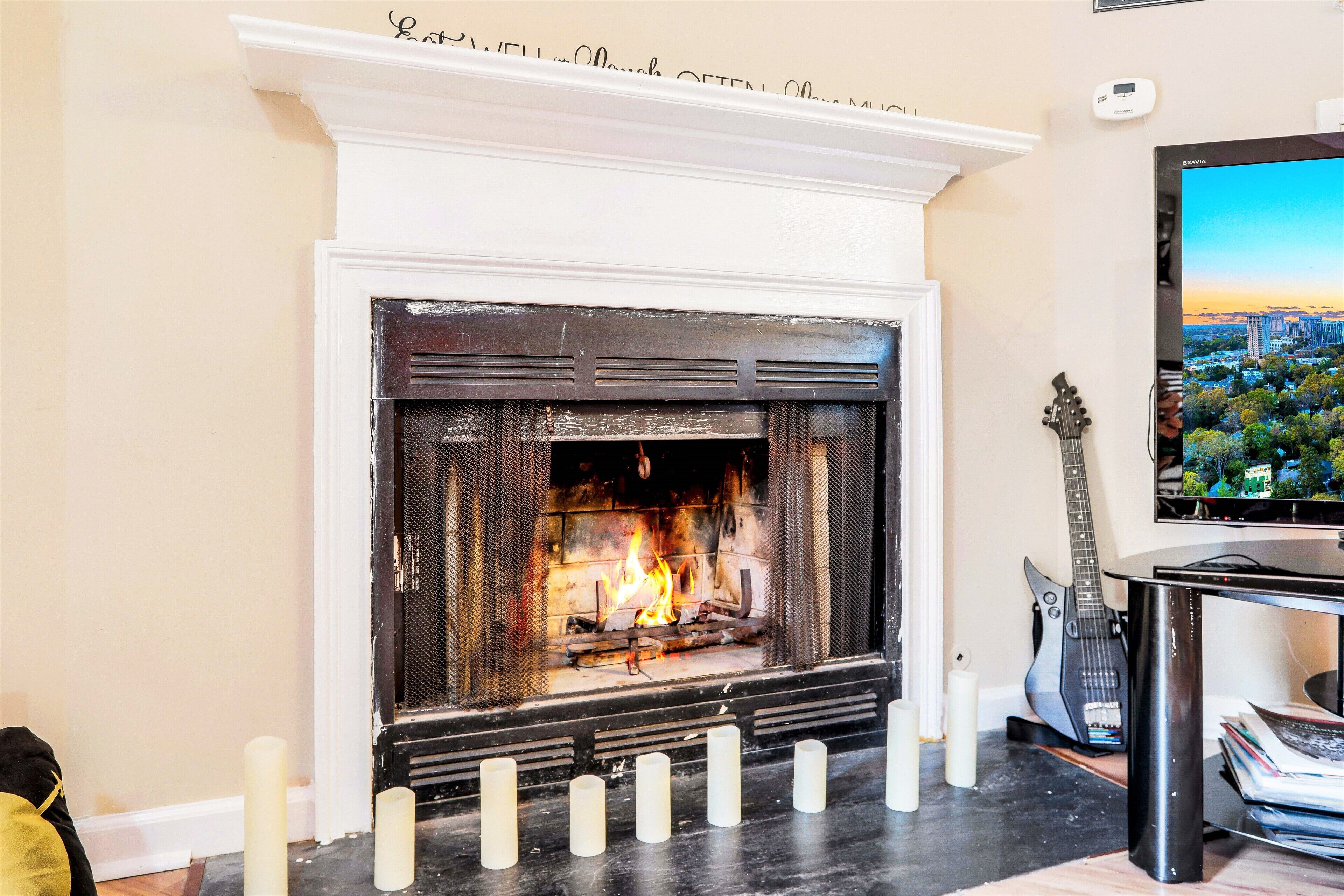 A fireplace with a TV mounted above it, a guitar, and a cityscape view.
