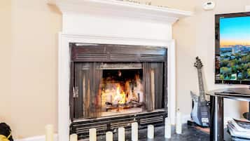 A fireplace with a TV mounted above it, a guitar, and a cityscape view.