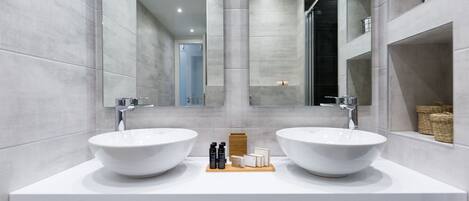 A modern bathroom with two large white sinks, a central mirror, and a tiled floor.