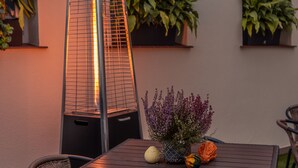 Un espace extérieur aménagé avec une table et des chaises, un radiateur et des plantes en pot.