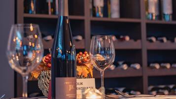 Una botella de vino y copas sobre una mesa con mantel estampado.