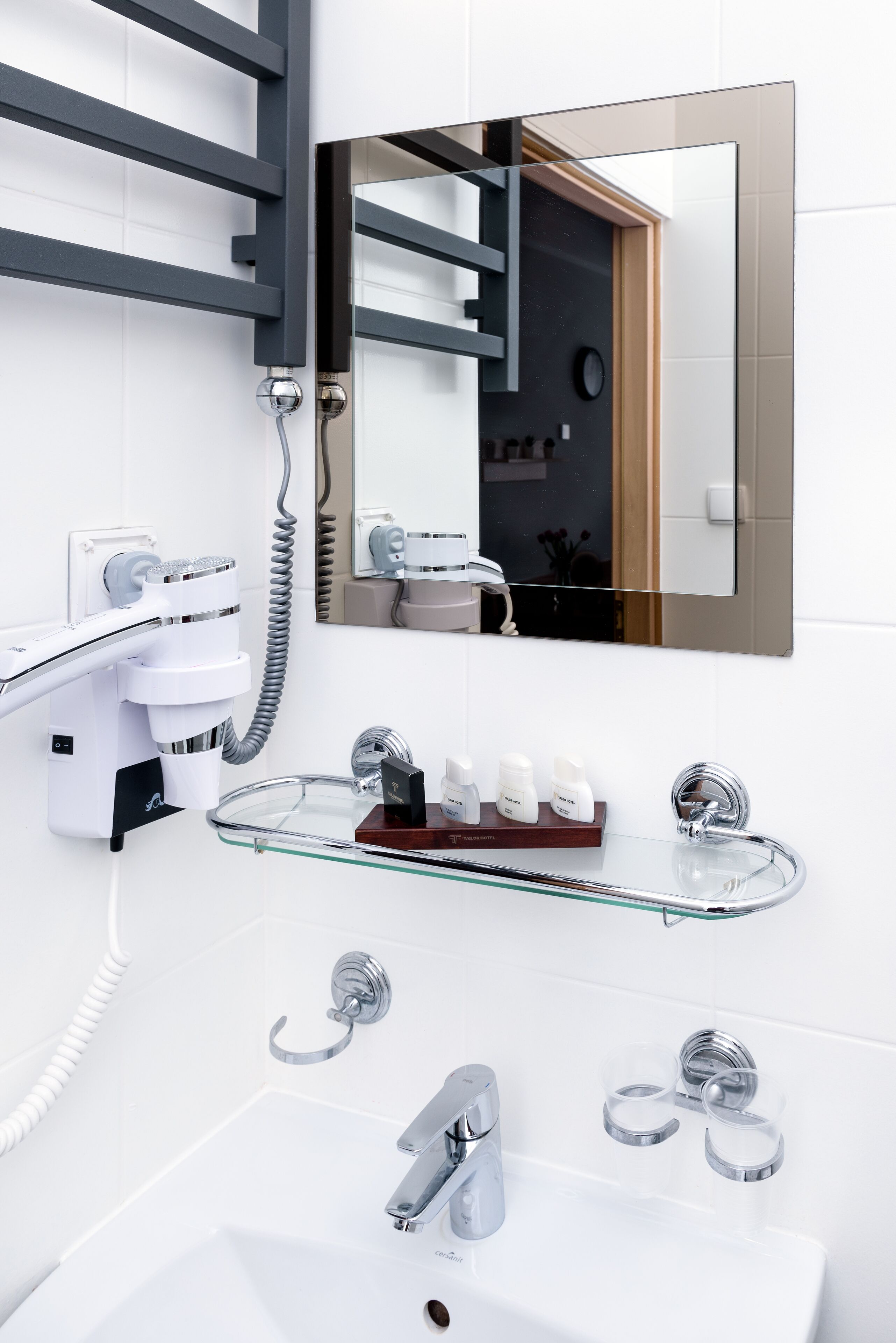A modern bathroom with a glass sink, chrome fixtures, a hairdryer, and a mirror.
