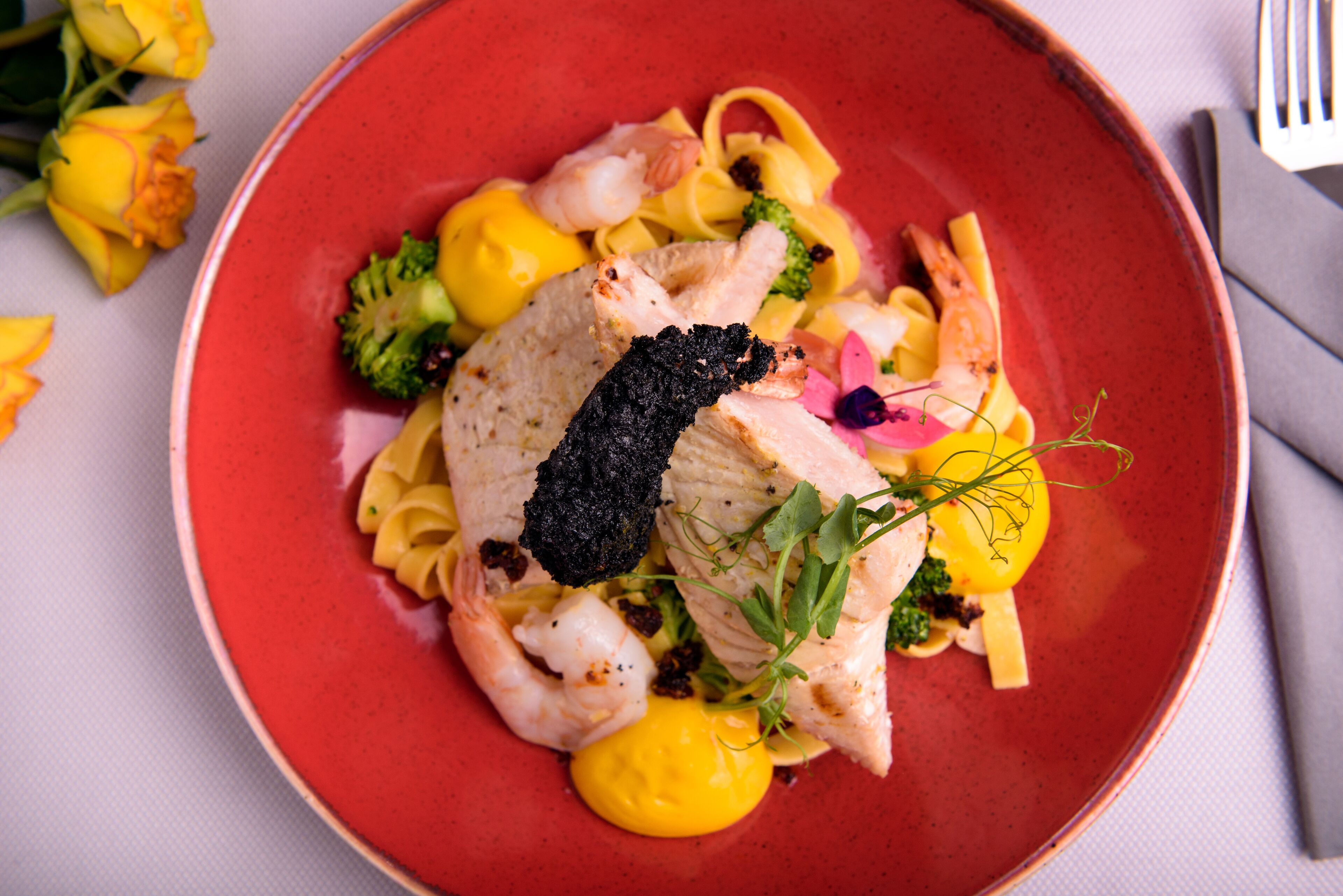 Un piatto di cibo con diversi ingredienti, tra cui pesce, gamberi e verdure.