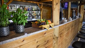 Un espace bar agrémenté de boiseries, un présentoir de fruits et une étagère remplie de boissons en bouteille.