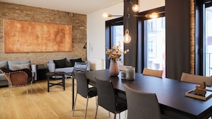 A modern dining area with a dark wooden table, grey upholstered chairs, and a hanging light fixture. - Søndergade - Strøget (Aarhus)