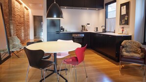 A modern kitchen with a large island, black cabinets, and a hanging pendant light. There is a dining area with a round table and chairs. - Amaliegade 10 B (Aarhus)