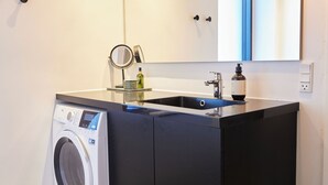 A compact laundry area with a washing machine, a sink, and a mirror. - Amaliegade 10 B (Aarhus)