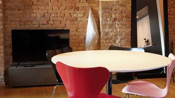 Un comedor con pared de ladrillo, una mesa redonda grande y sillas modernas.