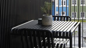 A balcony with a black metal table and chairs, a potted plant, and a view of colorful buildings. - Amaliegade 10 B (Aarhus)