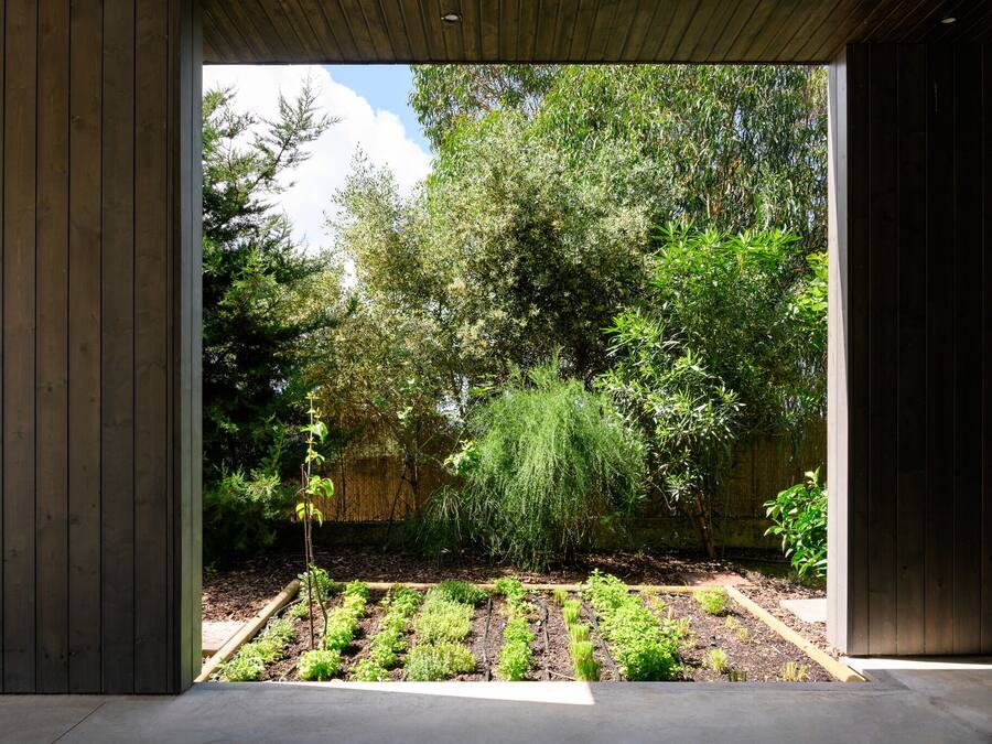 Un edificio moderno con fachada de madera y vistas a un jardín.