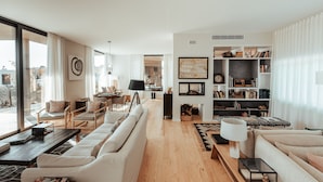A spacious living room with a large sofa, a coffee table, and a bookshelf.
