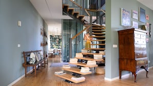 A spacious living area with a wooden staircase, a bench, and a large wooden cabinet.