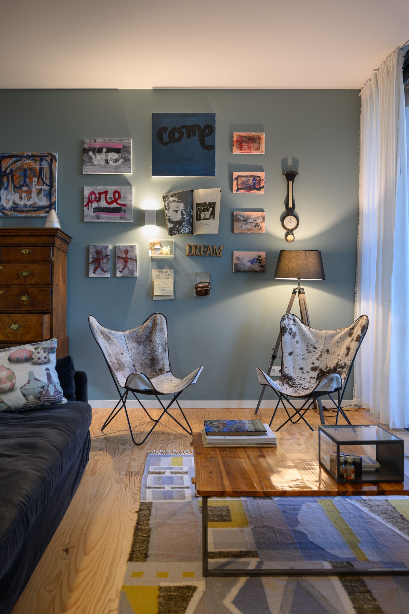 Un salón acogedor con pared azul, muebles de madera y varias obras de arte en las paredes.