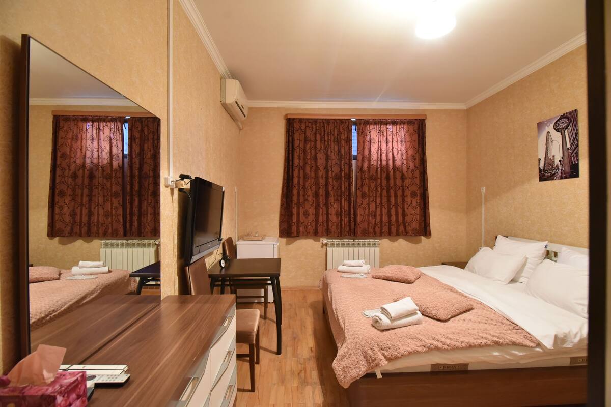 A hotel room with two beds, a desk, a chair, a TV, and a mirror.
