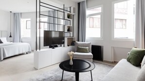 A modern living room with a sofa, a coffee table, a TV, and a bookshelf. - UPSTREET Luxury Apartments in Plaka (Athens)