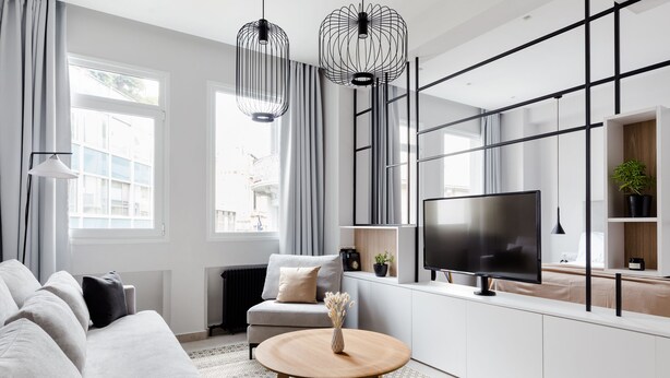 A modern living room with a sofa, a coffee table, and a TV on a white cabinet. - UPSTREET Luxury Apartments in Plaka (Athens)