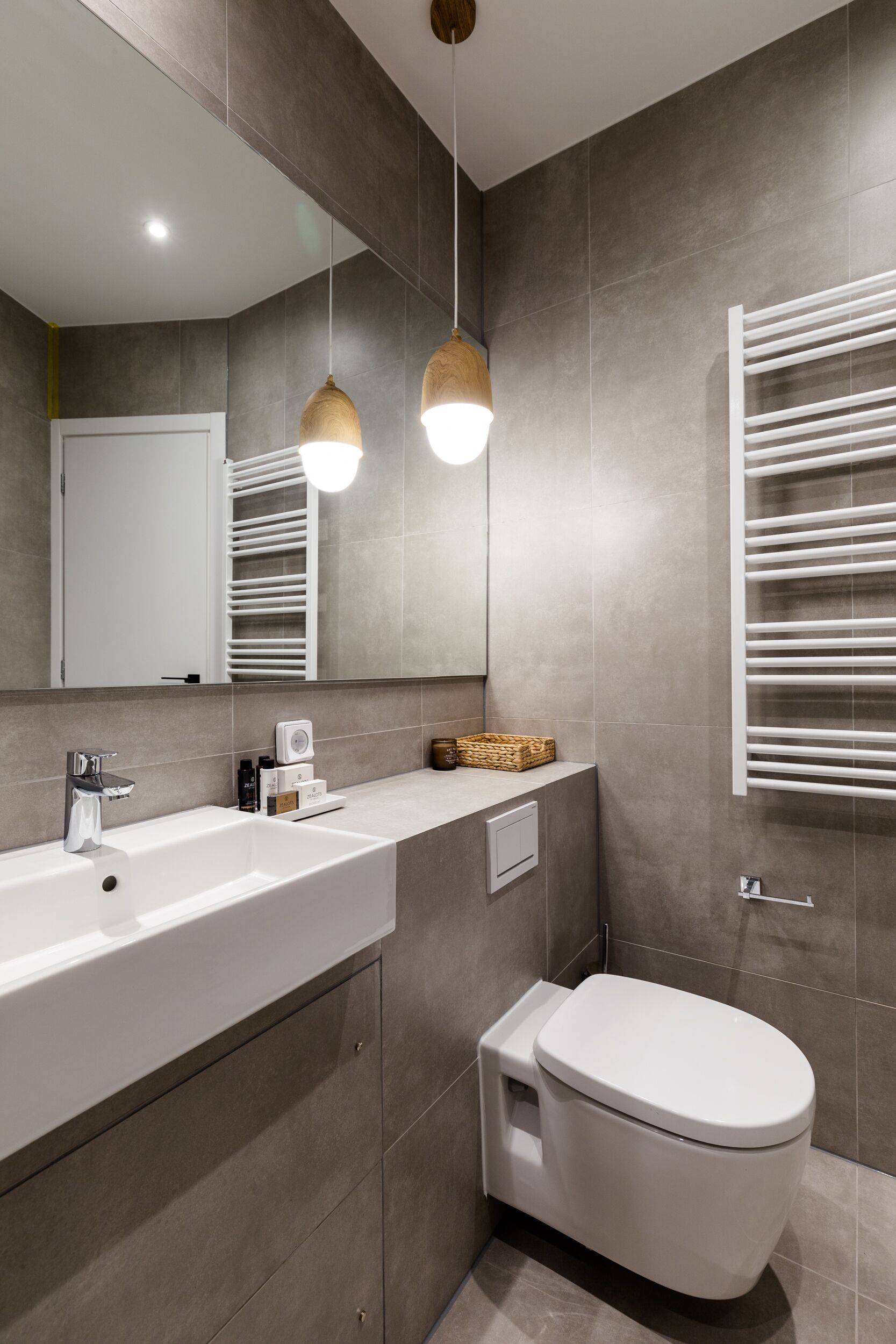 A modern bathroom with a white sink, a toilet, and a towel rack.