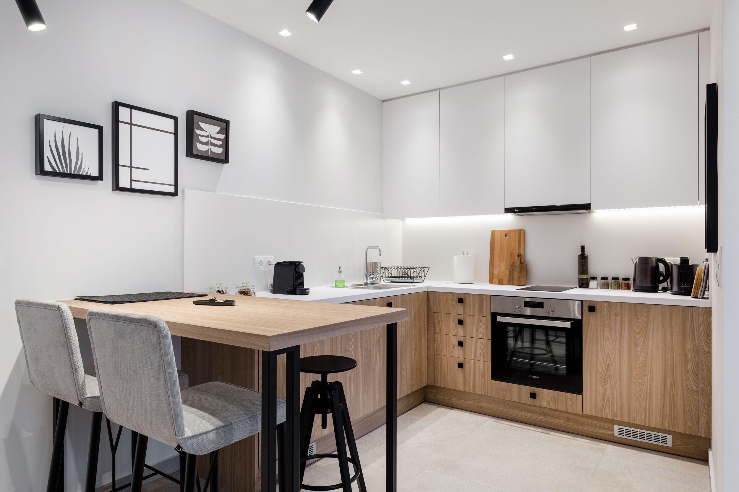 Een moderne keuken met een houten kookeiland, barkrukken en een inbouwoven.