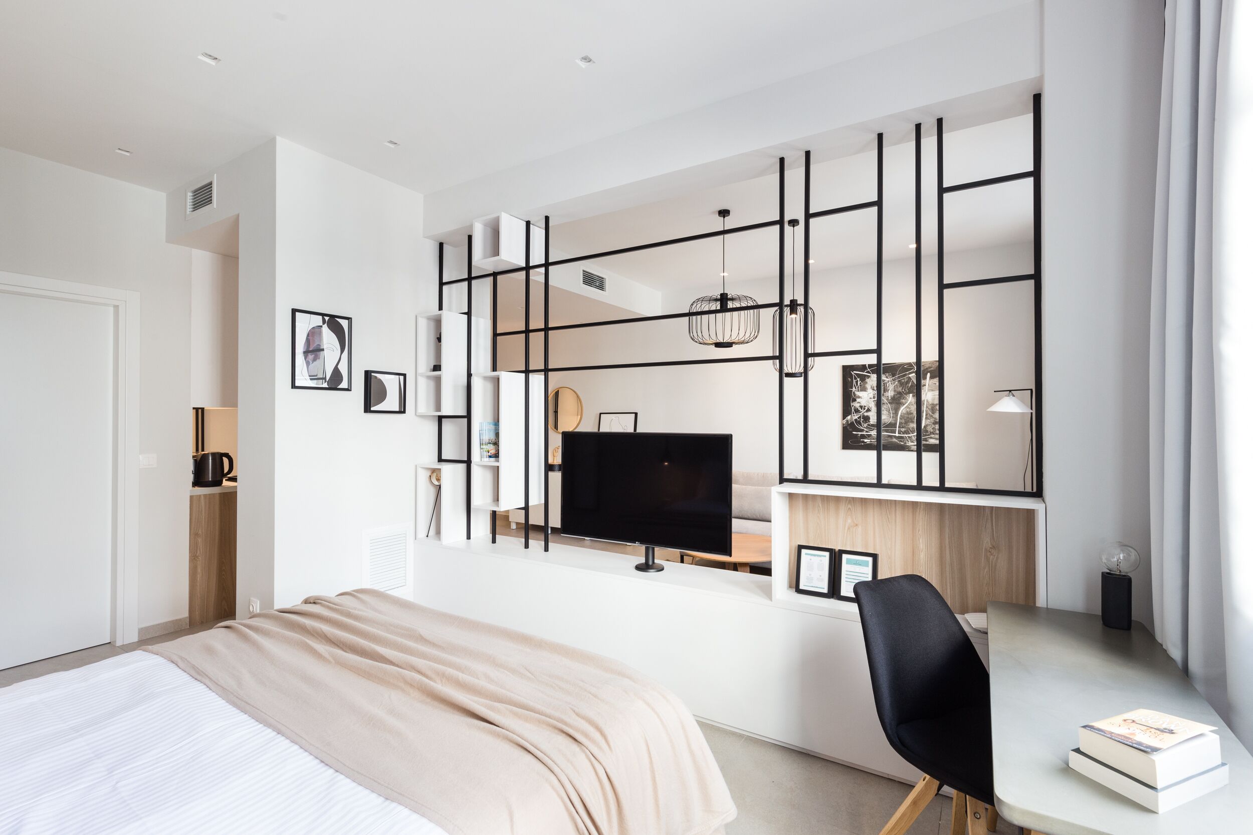 Ett modernt hotellrum med en stor säng, ett skrivbord med en stol, en platt-TV och en dekorativ väggpanel.