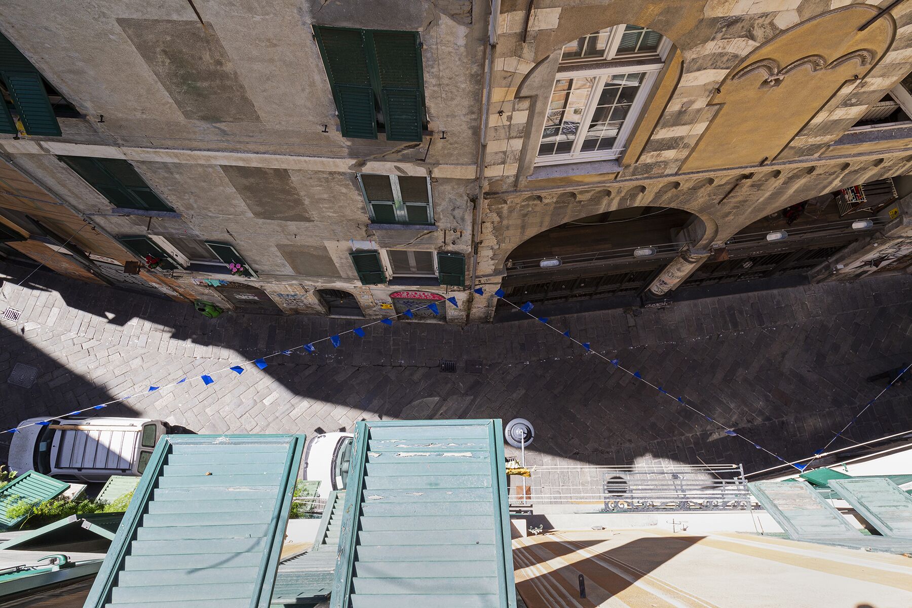 Una stretta via con una ripida salita, che conduce a un edificio con numerose finestre e un ampio ingresso ad arco.