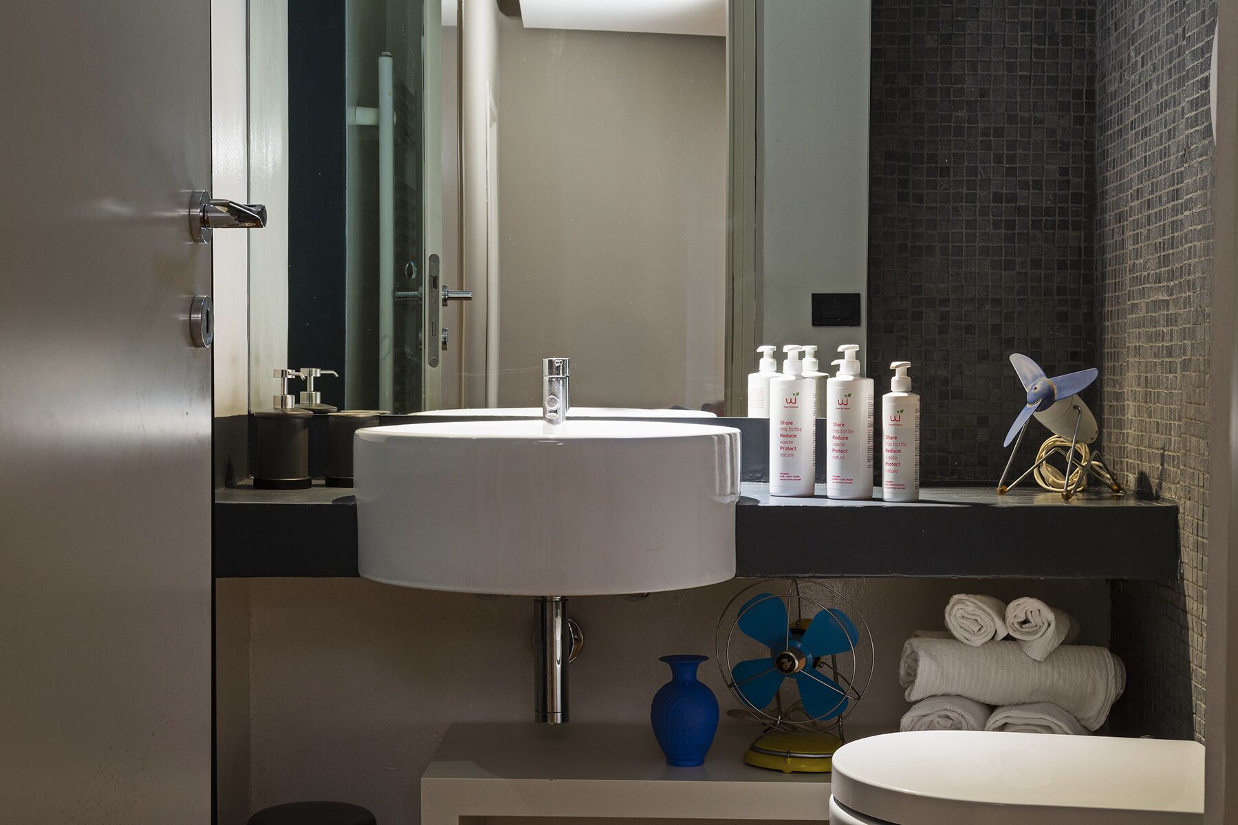 Un baño moderno con un lavamanos grande, espejo y toallero.
